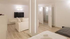 Ein modernes, minimalistisches Schlafzimmer mit Bett, Sofa und Fernseher.