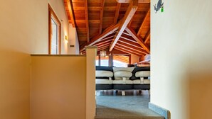 Eine Treppe führt zu einem Wohnbereich mit hoher Decke und Holzbalken.