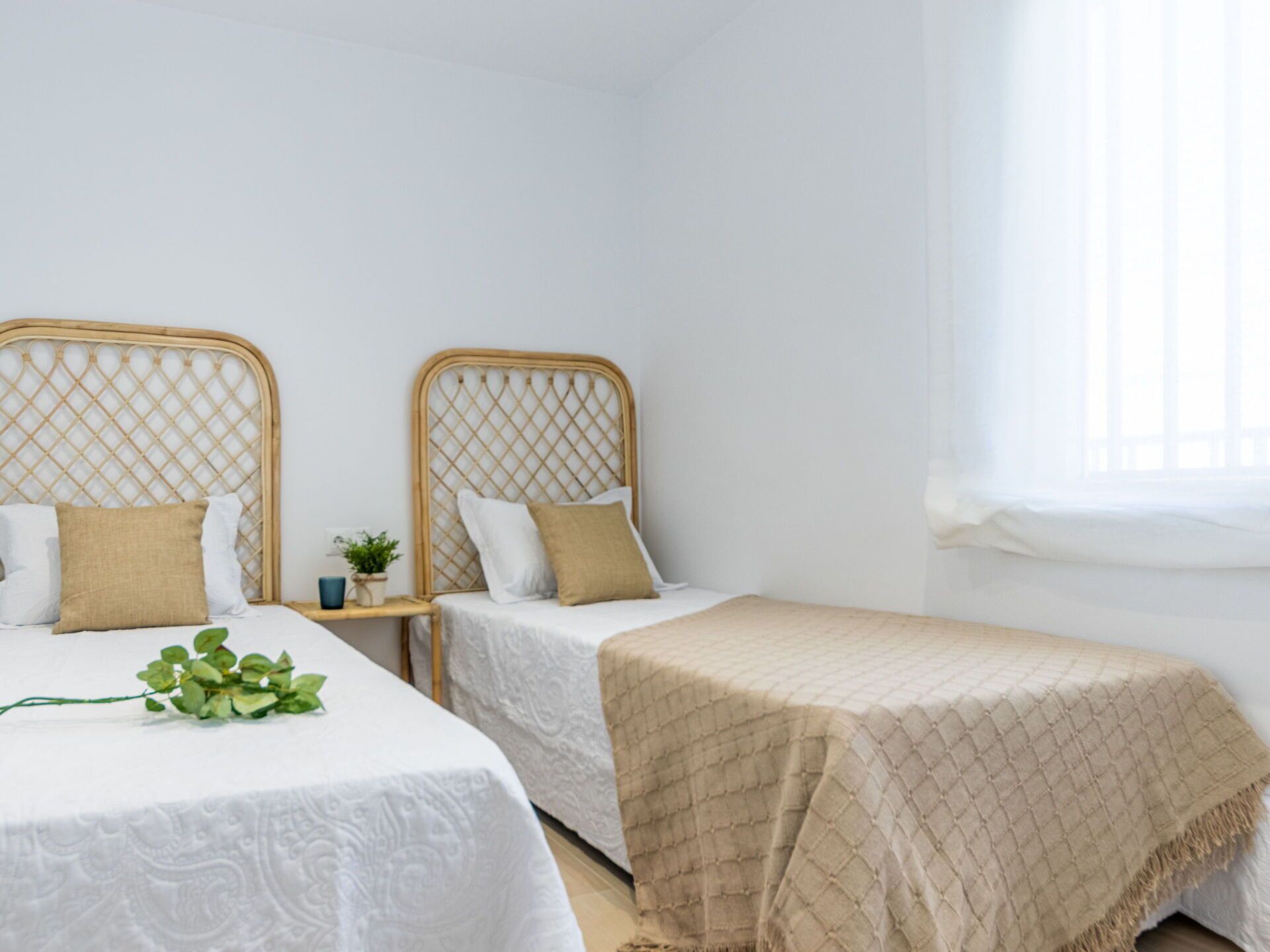 Een slaapkamer met twee eenpersoonsbedden, elk met een houten hoofdbord en witte beddengoed.