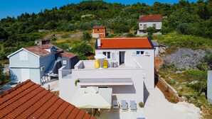 A modern house with a flat roof, a balcony, and a patio area with outdoor furniture.