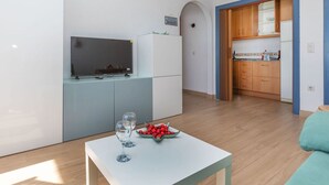 A modern kitchen with a TV, refrigerator, and wooden cabinets. - Lovely apartment for 4 people with pool, TV and terrace (Miami Platja)