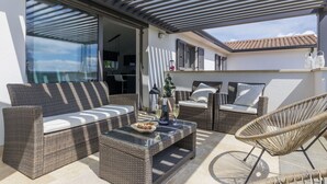 A covered outdoor seating area with wicker furniture, a glass-top table, and a view of the interior. - Wonderful  villa for 6 people with private pool, A/C, WIFI, TV and terrace (Pazin)