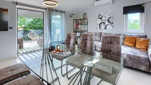 A modern living room with a glass dining table, grey sofas, and a ceiling light fixture. - Wonderful  villa for 6 people with private pool, A/C, WIFI, TV and terrace (Pazin)