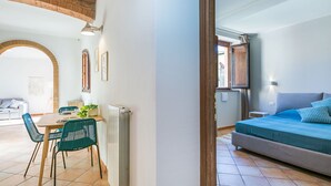 A cozy room with a bed, a dining area with chairs, and a radiator. - Wonderful private villa for 3 people with WIFI, A/C, TV, patio and pets allowed (Guardistallo)
