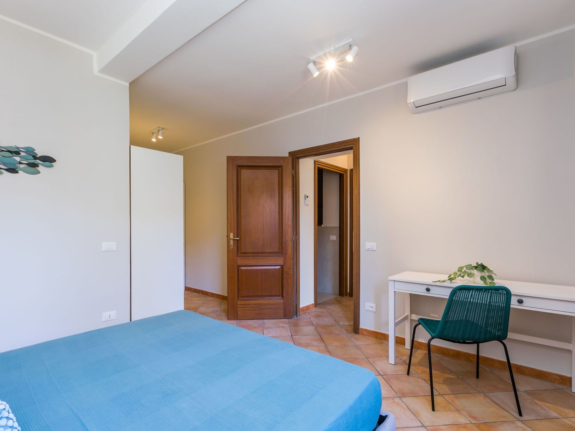 Ein Schlafzimmer mit Bett, Schreibtisch, Stuhl und Klimaanlage.