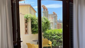 An open door leading to an outdoor patio with a table and chairs, a statue, and a view of buildings and greenery. - Wonderful private villa for 3 people with WIFI, A/C, TV, patio and pets allowed (Guardistallo)