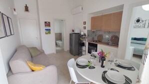 A modern living room with a sofa and a dining table set for four. - Nice apartment for 2 guests with WIFI, A/C, TV and terrace (Noto)
