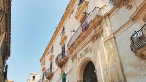 A historic building with ornate balconies and an arched entrance. - Nice apartment for 2 guests with WIFI, A/C, TV and terrace (Noto)