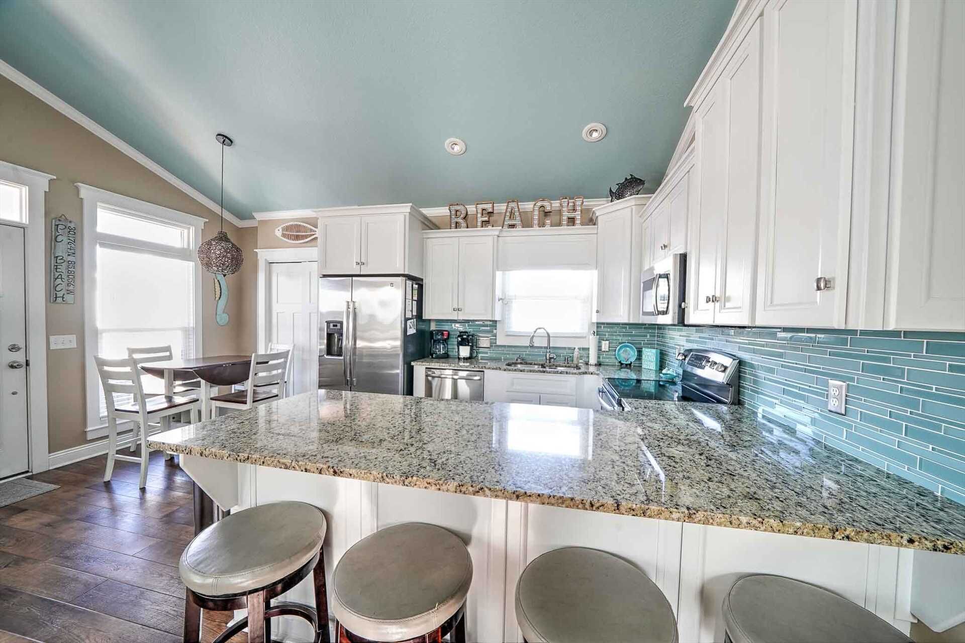 A modern kitchen with white cabinets, a granite countertop, and a central island with bar stools.