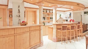 A wooden bar area with a curved counter, multiple stools, and a large column.