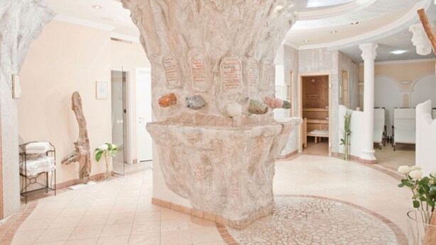 A spa area with a large rock centerpiece, a circular mosaic floor, and a reception desk.