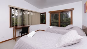A bedroom with two beds, a desk, and a window with blinds. - Casa Kabuae (Savegre)