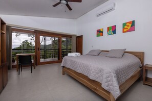Une chambre avec un lit, une chaise, une table et un balcon offrant une vue.
