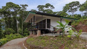 A modern house with a balcony, surrounded by lush greenery and a gravel path. - Casa Kabuae (Savegre)