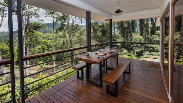 A wooden deck with a table and benches, overlooking a lush forest and mountains. - Casa Kabuae (Savegre)