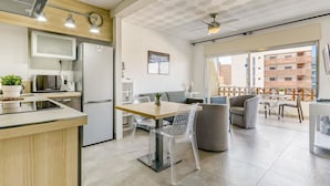 Een moderne keuken met een magnetron, koelkast en een eethoek met een tafel en stoelen.