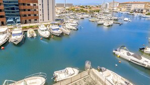 Een jachthaven met verschillende boten afgemeerd, omringd door gebouwen en een heldere lucht.
