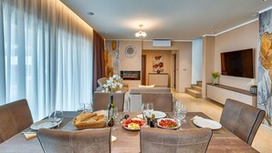 A modern dining area with a long table set for a meal, a sofa, and a television in the background. - Awesome home in Trget (Trget)