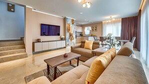 A modern living room with a sofa set, a coffee table, and a TV mounted on the wall. - Awesome home in Trget (Trget)