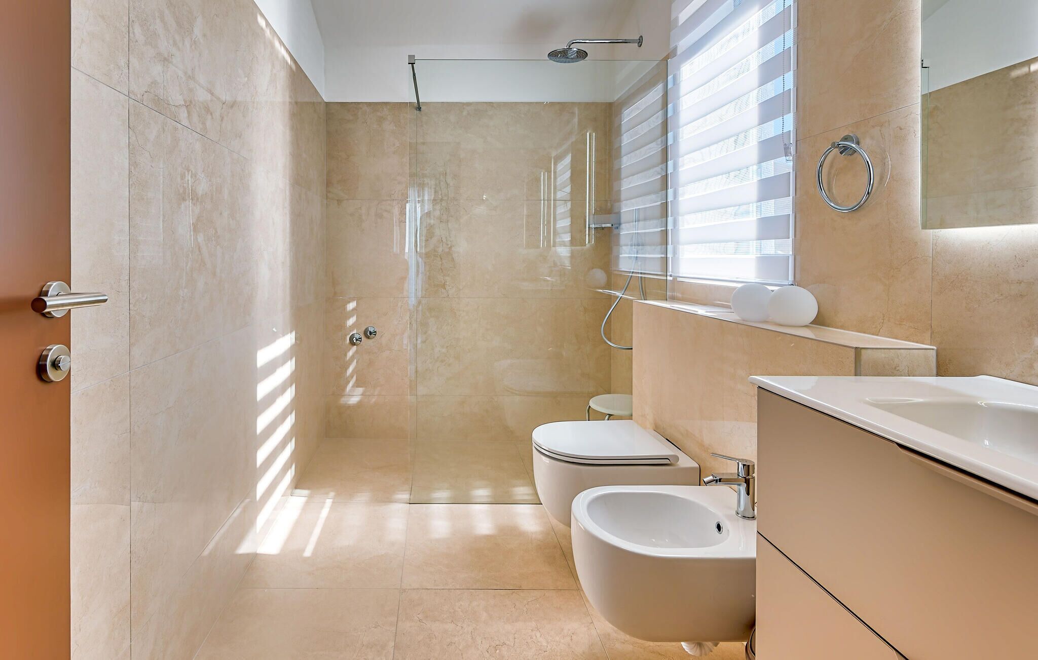 A modern bathroom with a walk-in shower, toilet, bidet, and a large mirror.