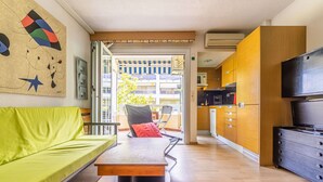 A modern living room with a green sofa, a wooden coffee table, and a view of the outside balcony. - Nice apartment for 2 guests with A/C, pool (Salou)