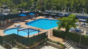 A swimming pool with sun loungers and umbrellas, surrounded by potted plants and a hedge. - Nice apartment for 2 guests with A/C, pool (Salou)