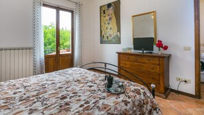 Une chambre à coucher avec un lit, une commode, un tableau et une fenêtre avec des rideaux.
