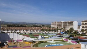 Et hotel med flere etager, sportsfaciliteter og udsigt til fjerne bjerge.