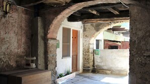 Une pièce rustique aux murs en briques apparentes, avec une porte en bois et une petite table agrémentée d’une plante.