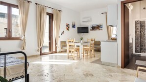 Un salon moderne comprenant un coin repas, un téléviseur fixé au mur et une vue sur l’extérieur par une fenêtre.
