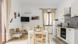 Une cuisine moderne avec des armoires blanches, un four encastré et un coin repas comprenant une table et des chaises en bois.