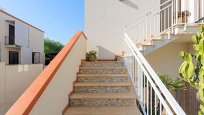A staircase with a white railing, leading to a balcony with a potted plant. - Lovely apartment for 6 people with A/C, WIFI, TV and terrace (San Vito Lo Capo)