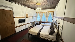A bedroom with two beds, a TV, a chandelier, and a window with curtains. - Kaleici Konak (Amasya)