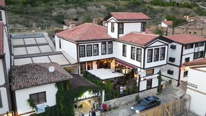 A traditional building with a restaurant on the ground floor, a balcony with a view, and a car parked in front. - Kaleici Konak (Amasya)