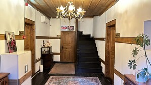 A staircase with wooden railings and a chandelier, leading to a room with a wooden door and a small table with a vase. - Kaleici Konak (Amasya)