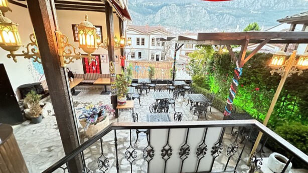 A courtyard with outdoor seating, decorative lanterns, and a view of a mountainous landscape. - Kaleici Konak (Amasya)