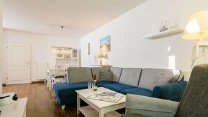 Un saló modern amb un sofà modular, una taula de centre i una zona de menjador amb un penjó.