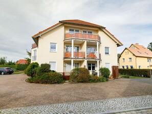 Stunning residential building with a central balcony and beautifully manicured garden.