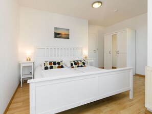 Cozy retreat with a white bed frame, bedside tables, and a large wardrobe.