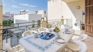 A balcony with a table set for two, featuring a coffee maker, cups, saucers, a tray with a fruit bowl, and a washing machine. - Beautiful apartment for 6 guests with WIFI, A/C, TV and terrace (San Vito Lo Capo)