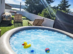 An outdoor swimming pool with inflatable toys, surrounded by a patio area with chairs and a table.