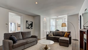 A modern living room with two grey sofas, a round coffee table, and a floor lamp.