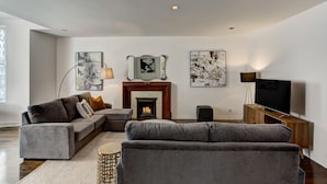 A modern living room with a sectional sofa, a fireplace, and artwork on the walls.