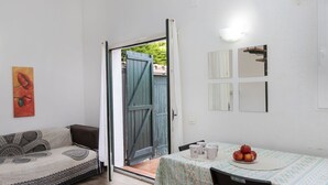 Una habitación con una cama, una mesa con mantel estampado y un cuadro en la pared.