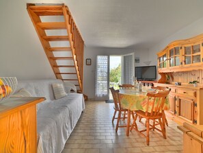 Enjoy a spacious open-plan living space with a loft bedroom, dining area, and large window offering a view of the outdoors.