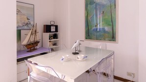 A dining area with a white table, chairs, and a painting on the wall. - Nice apartment for 4 people with pool, A/C, WIFI, terrace and pets allowed (Bordighera)