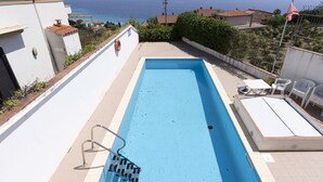 A rectangular swimming pool with a metal ladder, white lounge chairs, and a view of the sea. - Nice apartment for 4 people with pool, A/C, WIFI, terrace and pets allowed (Bordighera)