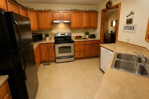 A kitchen with wooden cabinets, a stainless steel refrigerator, an oven, a sink, and a dishwasher.