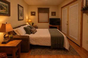 A neatly arranged bedroom with a bed, bedside tables, a television, and a wardrobe. - Cardinal's Nest • Sleeps 10 • Near Dollywood, Pigeon Forge & Gatlinburg (Sevierville)