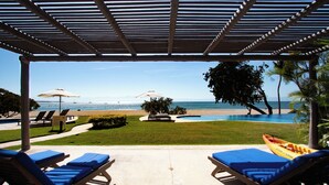 Zona junto a la piscina con sillones reclinables, una piscina pequeña y vistas a la playa y el océano.